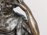 a bronze statue of a woman sitting on a chair