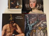 plusieurs livres posés sur une table, à côté d'un tableau représentant un homme coiffé d'un chapeau blanc