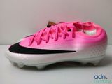 La chaussure de foot rose et noire se trouve sur une surface blanche.