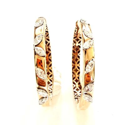 une paire de boucles d'oreilles créoles en or et diamants sur fond blanc