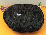 a black round pillow on a yellow table
