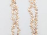 un collier de perles blanches avec un fermoir en or sur fond blanc