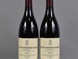 two bottles of red wine sitting on top of a table