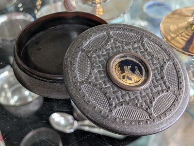 a small metal box with a lid on a glass table