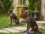 deux statues de chiens assis dans l'herbe, à l'extérieur