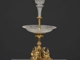 un vase en or et en cristal posé sur un socle et orné d'un oiseau