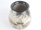 a vase with a painting on it on a white surface