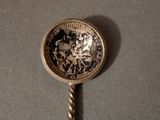 a silver spoon with a coin on it on a table