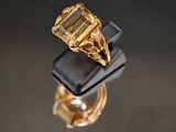 une image représentant une bague en or sertie d'une émeraude, posée sur un écrin noir