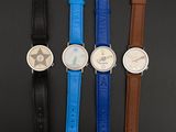 four different colored watches are lined up on a black surface