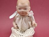 a small doll that is sitting on a pink surface