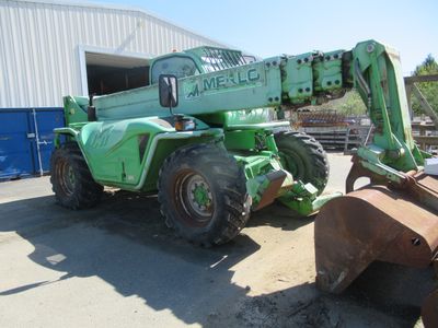 a green crane that is parked in front of a building