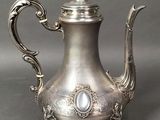 an antique silver tea pot with a bird on top of it