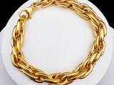 gold plated chain bracelet on a white plate on a black background