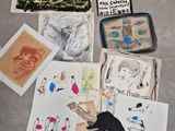 une personne debout sur le sol, à côté d'une pile de dessins