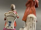 pair of porcelain figurines of a woman and a man sitting on a chair