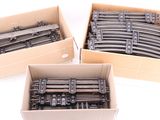 three cardboard boxes filled with different types of train tracks on a white surface