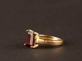 gros plan d'une bague en or avec une pierre rouge