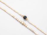 a close up of a necklace with pearls and a black bead