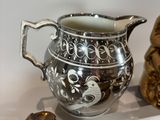 a silver pitcher sitting on top of a shelf next to other items