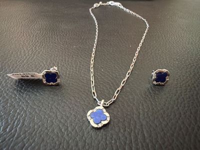 silver necklace and earrings with blue stones on a leather surface