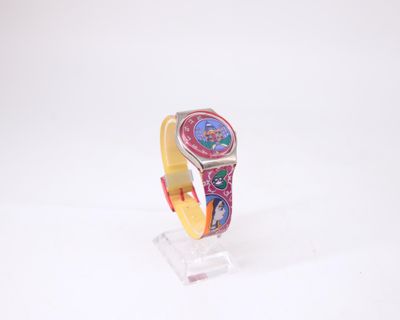 une montre colorée posée sur un socle transparent, sur une surface blanche