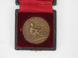 a gold medal in a red case on a white surface