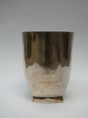 une tasse en argent posée sur une surface blanche
