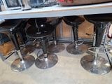 four black stools sitting under a table in a kitchen