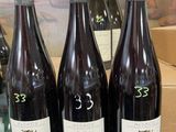 three bottles of wine are sitting on a table in front of a painting