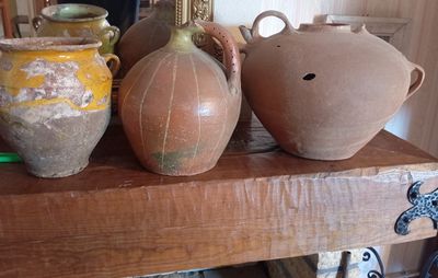 un homme en train de prendre une photo de trois vases posés sur une étagère