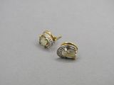 une paire de boucles d'oreilles en or et diamants posées sur une surface grise