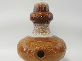 un vase marron avec un couvercle blanc et un socle marron