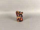 a small vase sitting on top of a table next to a white wall