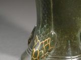 a green vase with a gold design on it