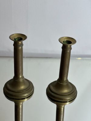 pair of antique brass candlesticks on glass table with white background