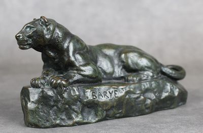 une statue en bronze représentant un lion couché sur un rocher