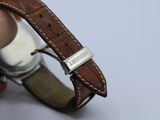 someone is holding a watch with a brown leather band