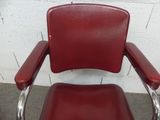 a red leather chair with chrome arms and a black seat
