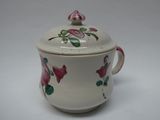 une tasse blanche ornée de fleurs roses, posée sur une surface blanche