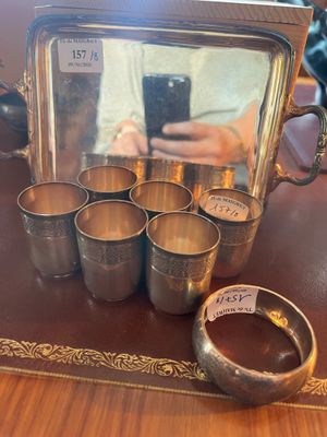 une théière et des tasses en argent posées sur une table avec un miroir