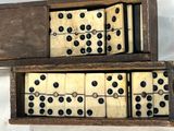 deux boîtes en bois contenant des dominos, posées sur une surface blanche
