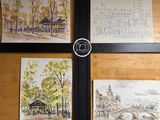 quatre tableaux accrochés au mur d'une pièce où se trouve une horloge
