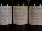 three bottles of red wine are lined up on a table