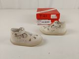 pair of white baby shoes on a white surface with a red box in the background