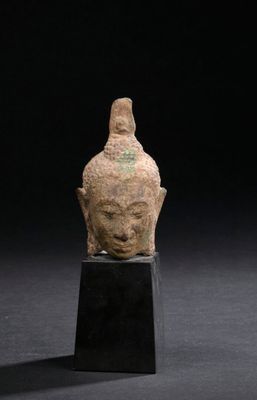 an ancient bronze head of a buddha on a black stand