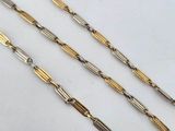 three different lengths of gold and silver chains on a white surface