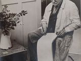 a black and white photo of an old man sitting on a chair