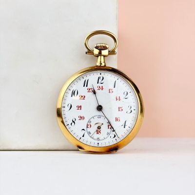 un gros plan d'une montre de poche en or posée sur une table