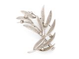 a close up of a silver brooch with leaves on it